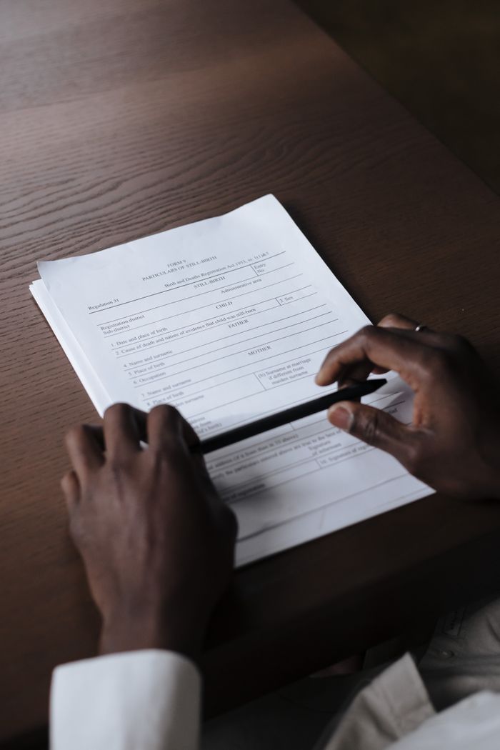 Hands holding a pen and reviewing a contract on a wooden table, creating a professional business setting.